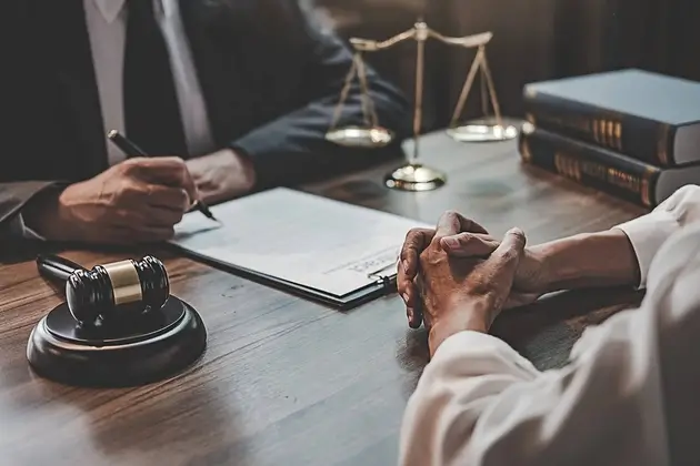 A legal blog worthy of our clients, as seen here between an attorney and client at a desk, writing on a pad of lined paper.